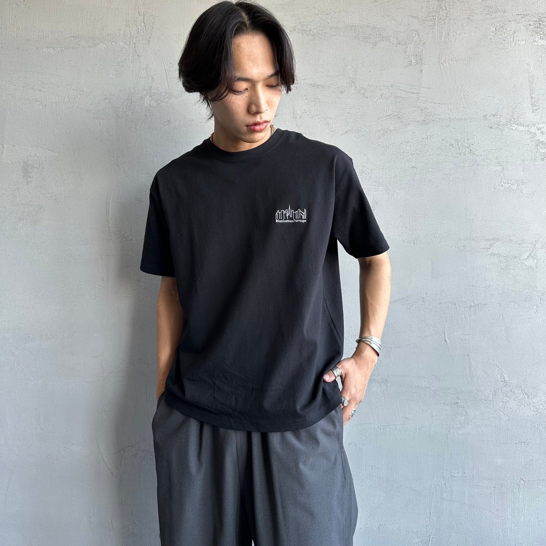 MANHATTAN PORTAGE [マンハッタンポーテージ] 別注 ランダムロゴ バックプリントTシャツ [25SSMP-IN66-JF] BLACK &&モデル身長：179cm 着用サイズ：L&&