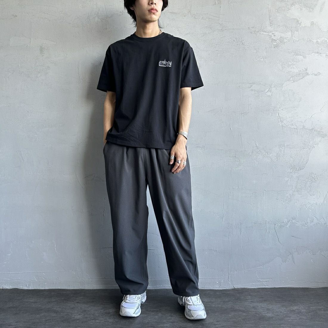 MANHATTAN PORTAGE [マンハッタンポーテージ] 別注 ランダムロゴ バックプリントTシャツ [25SSMP-IN66-JF] BLACK &&モデル身長：179cm 着用サイズ：L&&