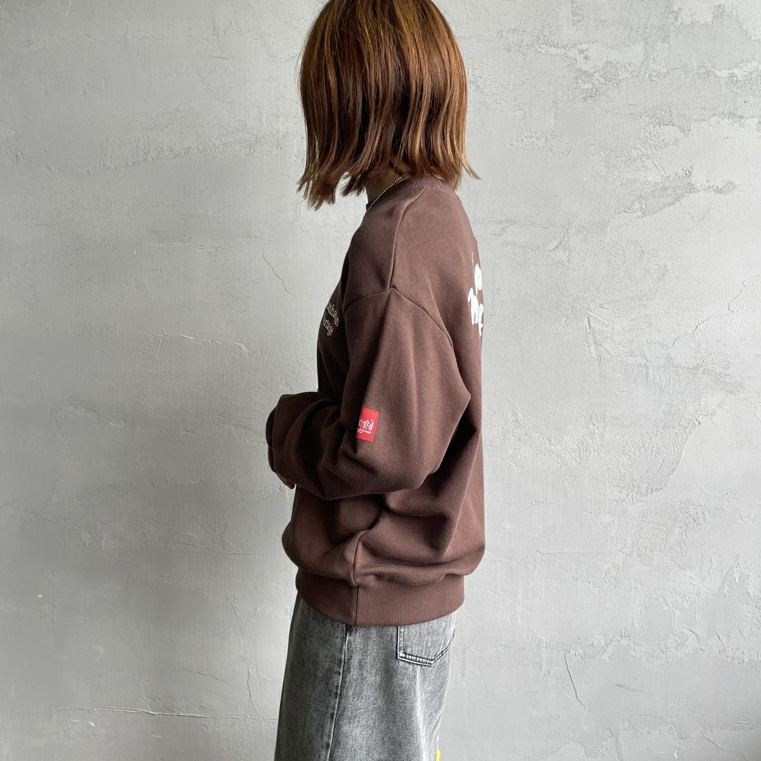 MANHATTAN PORTAGE [マンハッタンポーテージ] 別注 手書き風バック刺繍クルーネックスウェット [25FWMP-IN69-JF] D.BROWN &&モデル身長：158cm 着用サイズ：S&&