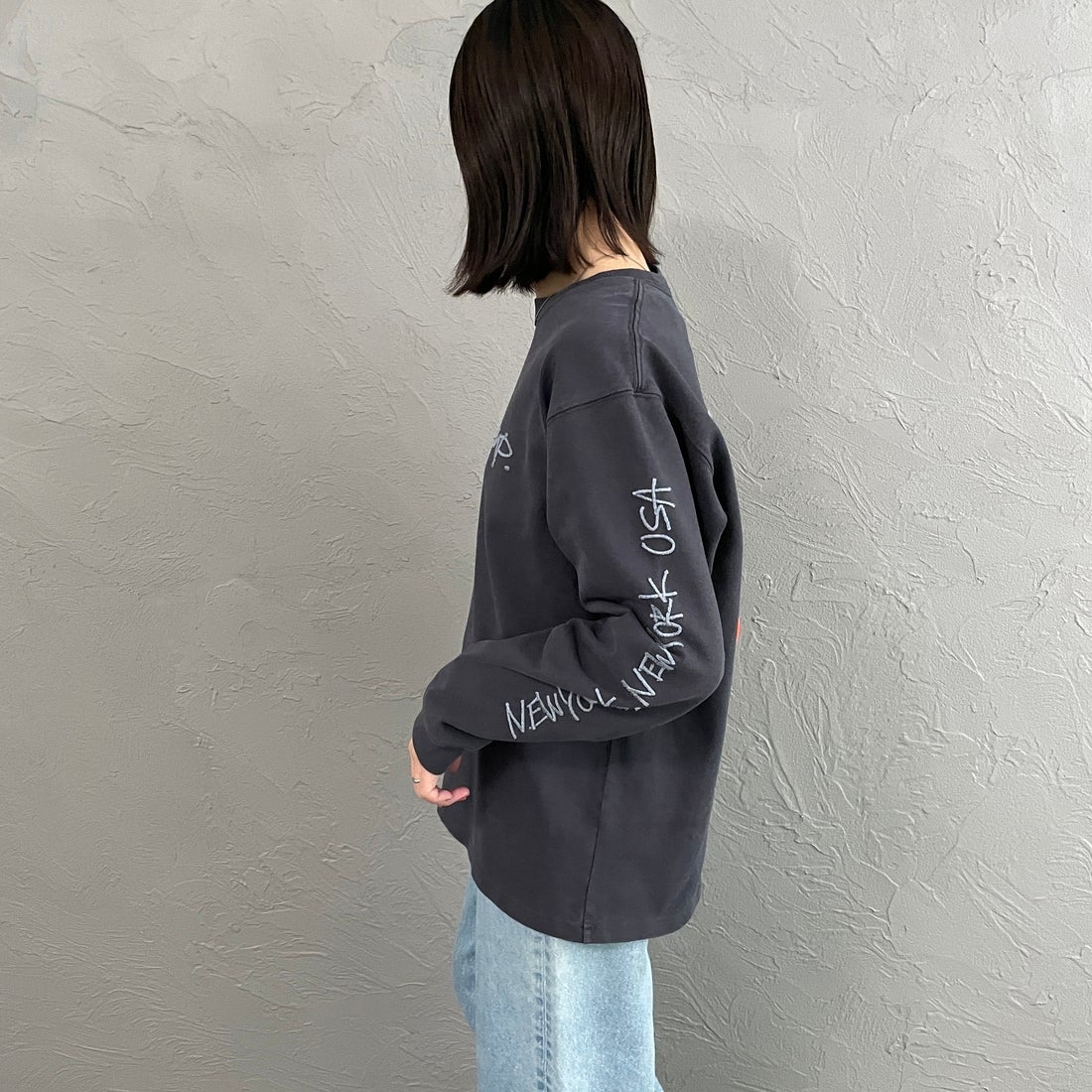 MANHATTAN PORTAGE [マンハッタンポーテージ] 別注 ピグメント染め 手書き風バックロゴ刺繍ロングスリーブTシャツ [26SSMP-IN84-JF] CHARCOAL &&モデル身長：160cm 着用サイズ：S&&