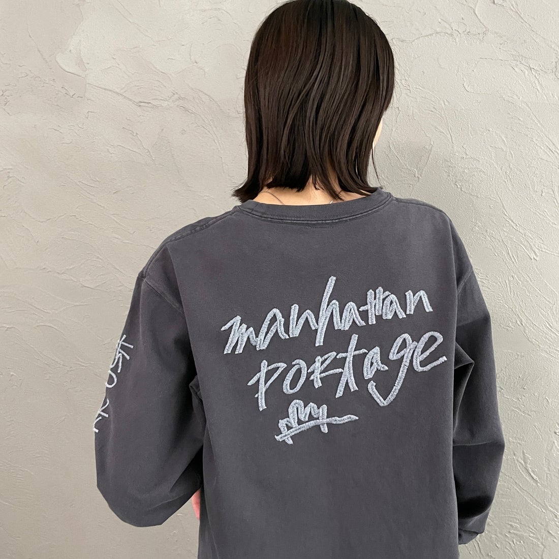 MANHATTAN PORTAGE [マンハッタンポーテージ] 別注 ピグメント染め 手書き風バックロゴ刺繍ロングスリーブTシャツ [26SSMP-IN84-JF] CHARCOAL &&モデル身長：160cm 着用サイズ：S&&